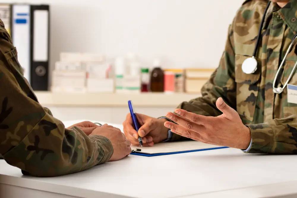 Médecin militaire en uniforme échangeant avec un candidat lors d'une visite médicale d'incorporation pour l'armée.