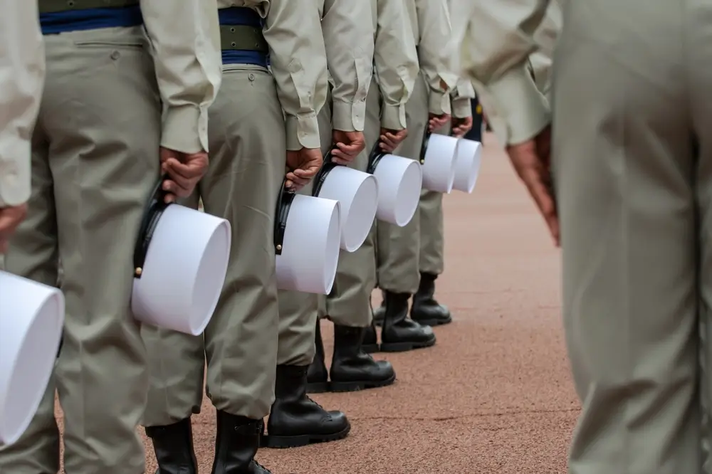 Légionnaires en uniforme alignés lors d'un défilé militaire, tenant leur képi blanc à la main.