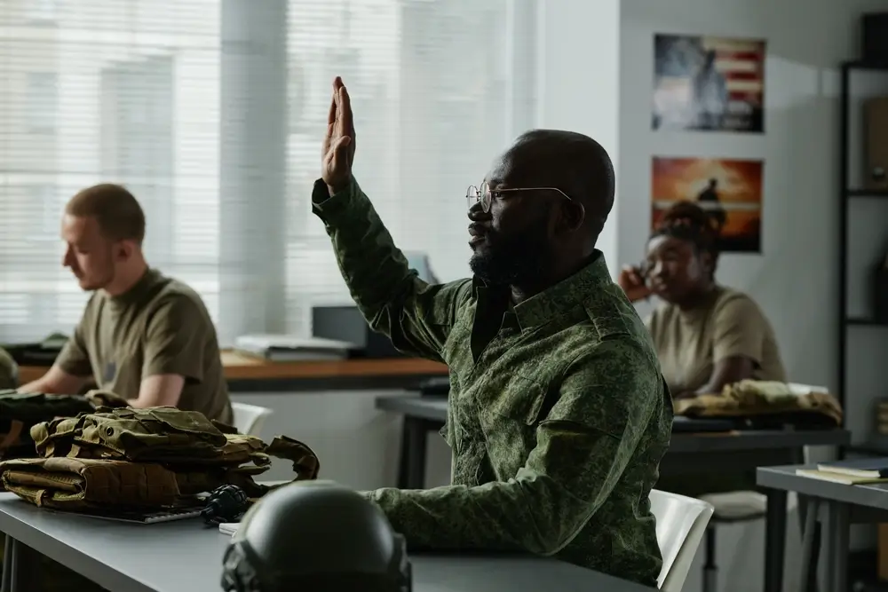 Soldat en treillis levant la main lors d'un cours de français dans une salle d'instruction militaire.