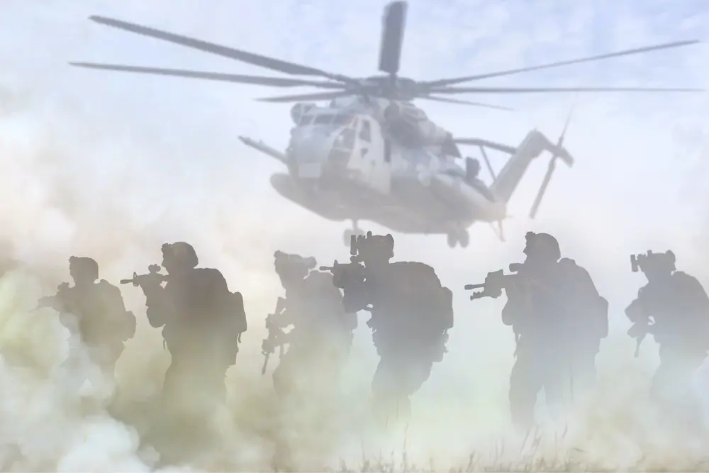 Militaires équipés en mission OPEX avançant dans la poussière sous un hélicoptère en zone aride.