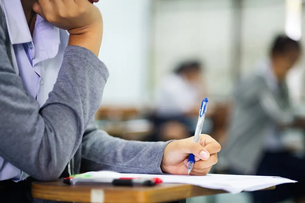 Candidat concentré rédigeant son test psychotechnique sur papier dans une salle d'examen.
