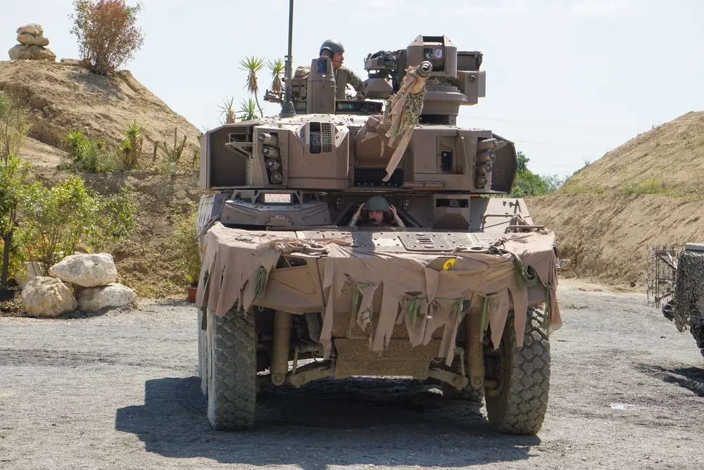 Engin blindé de reconnaissance Jaguar du 1er REC en manœuvre sur un terrain militaire poussiéreux à Carpiagne.