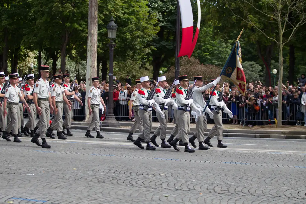 Légionnaires de la Légion étrangère défilant en uniforme avec leur képi blanc lors d'une parade militaire.
