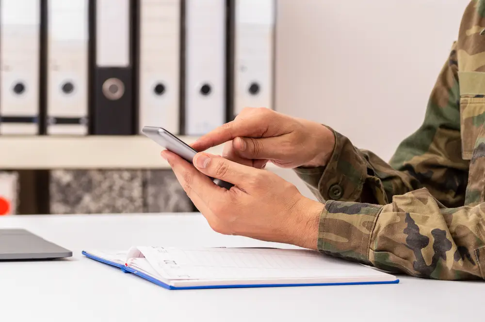 Soldat en uniforme qui consulte son téléphone portable pendant un quartier libre