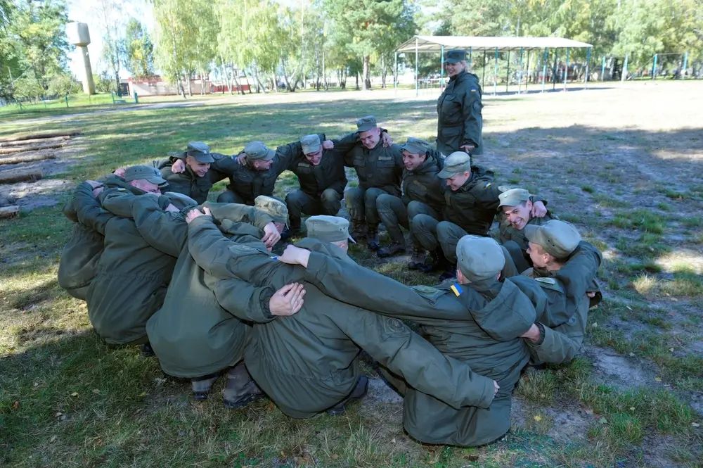 Recrues militaires en formation effectuant un exercice de cohésion en cercle lors des tests de sélection.