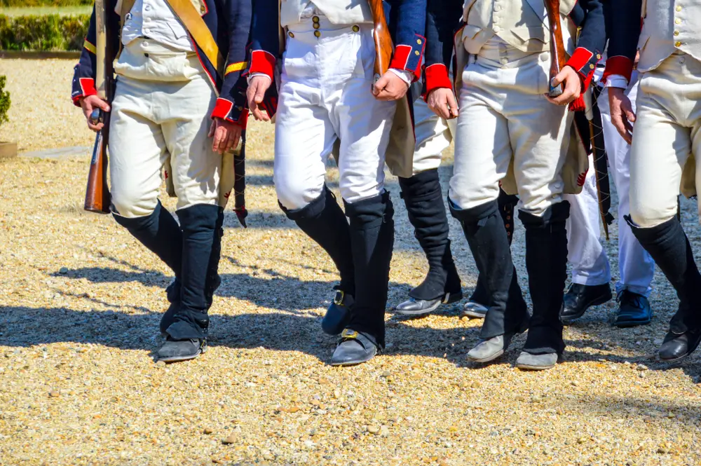 Soldats en uniforme du XIXe siècle marchant, fusils en main, lors d'une reconstitution de bataille historique.