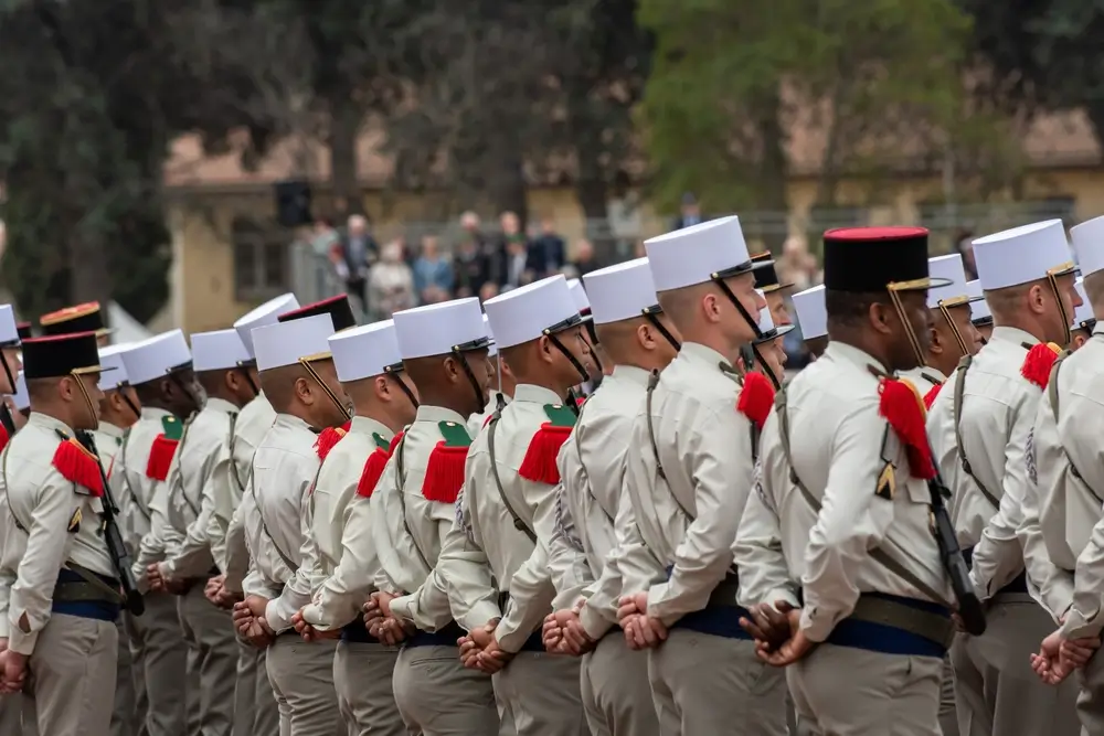 Légionnaires en képi blanc et uniforme de parade alignés lors d'une revue militaire au sein de leur régiment.