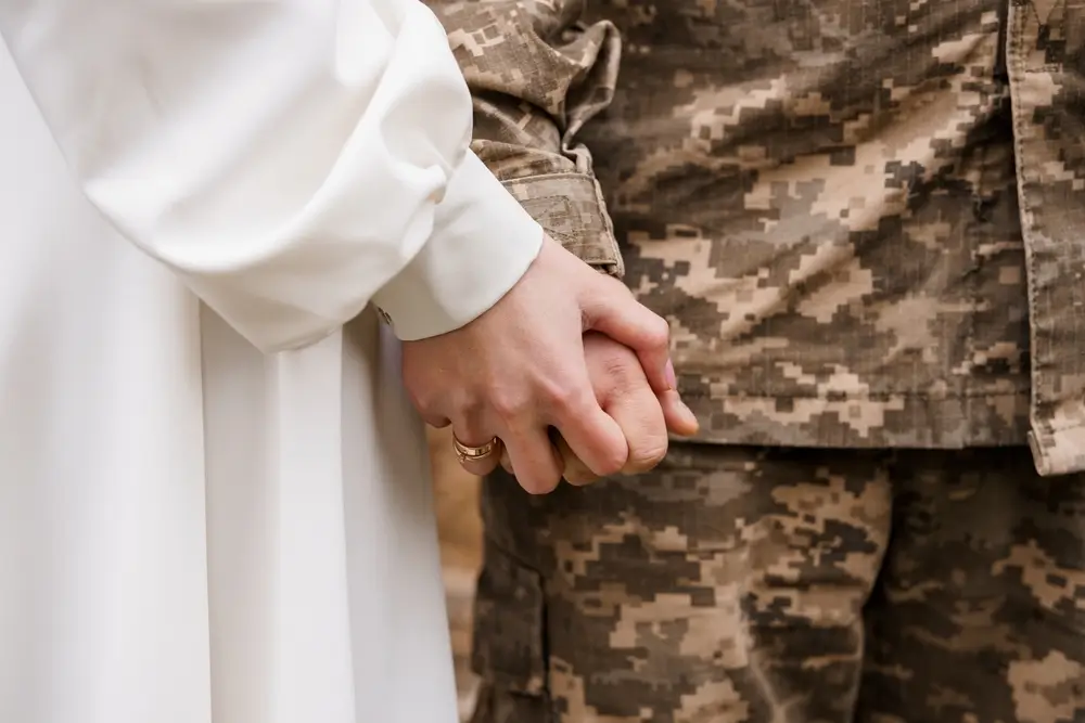 Un soldat en uniforme et son épouse se tenant la main lors d'une cérémonie de mariage militaire.