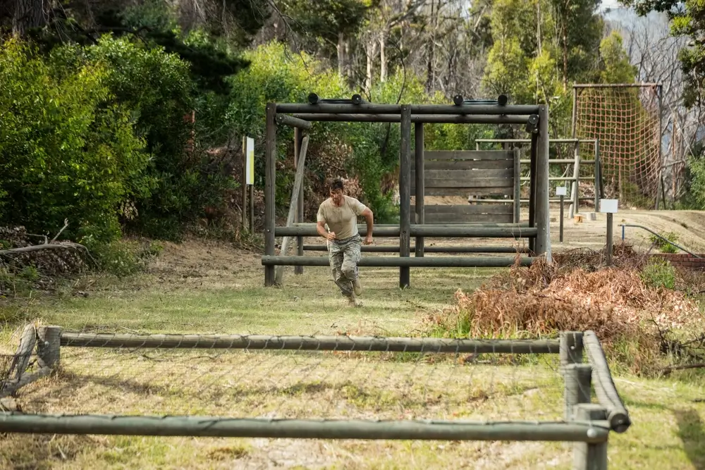 Recrue militaire franchissant un parcours d'obstacles lors d'un entraînement physique intense de sélection.