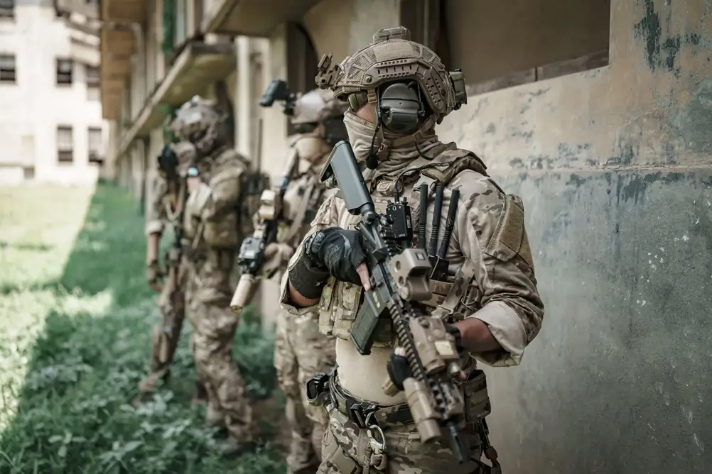 Unité de soldats des forces spéciales en équipement tactique complet avec fusils d'assaut lors d'un exercice militaire.