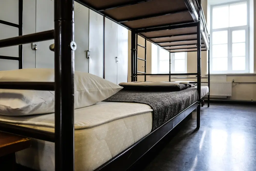 Dortoir d'une caserne militaire avec lits superposés faits au carré et casiers métalliques parfaitement rangés.