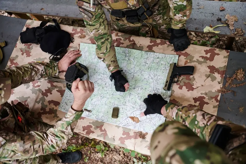 Officier et soldats étudiant une carte tactique lors d'un briefing de commandement avant une opération sur le terrain.