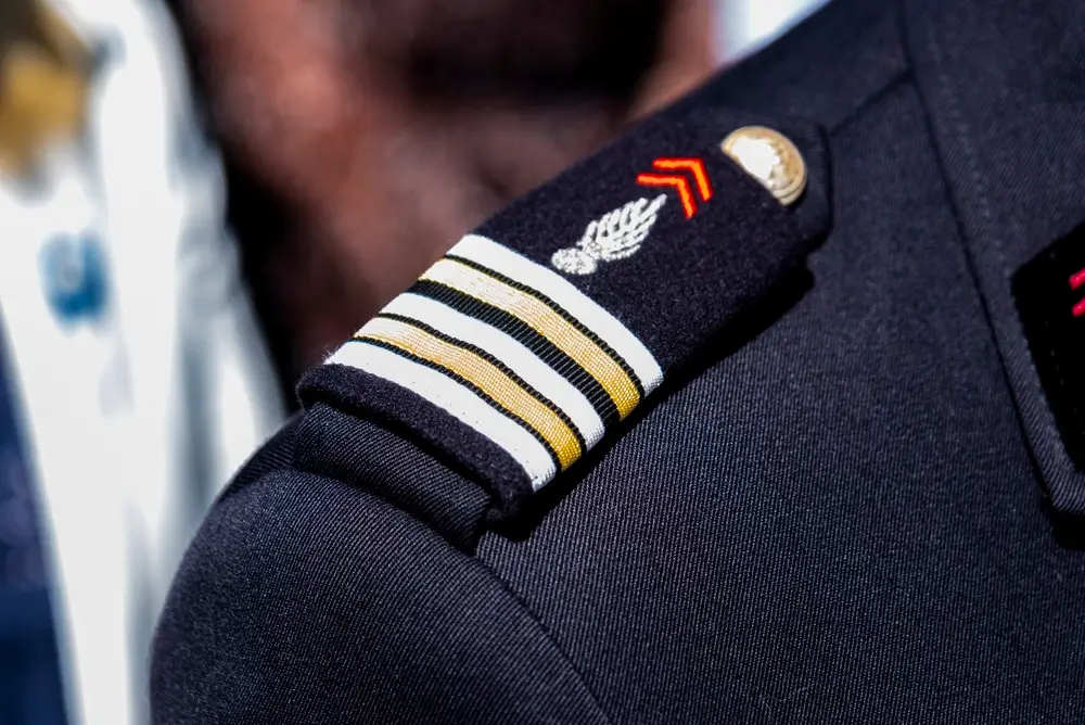 Galons de sous-officier et grenade brodée sur l'épaulette d'un uniforme militaire, illustrant l'avancement de carrière.